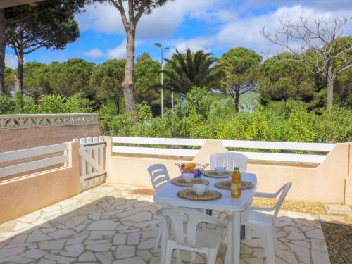 einen blauen Tisch und Stühle auf einer Terrasse mit Bäumen in der Unterkunft Holiday Home Les Maisons du Rivage Bleu by Interhome in Narbonne-Plage