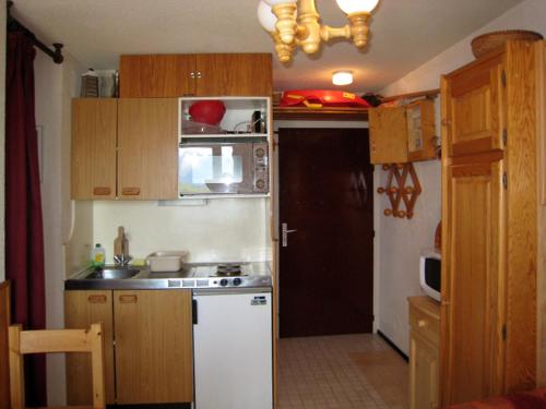 a small kitchen with wooden cabinets and a white refrigerator at Apartment Val d'Huez by Interhome in L'Alpe-d'Huez