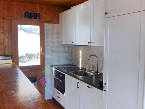 een keuken met witte kasten en een spoelbak bij Chalet Sven Heul by Interhome in Nendaz