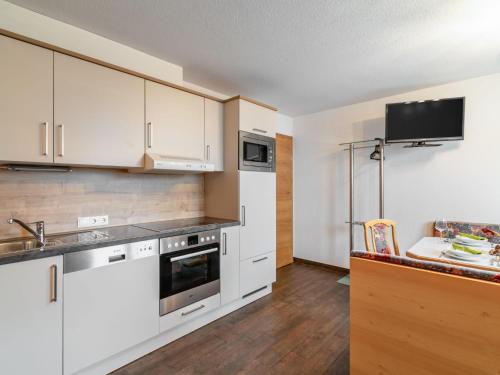 een keuken met witte kasten en een tv aan de muur bij Apartment Christoph - KPL370 by Interhome in Kappl