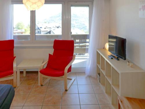 a living room with two red chairs and a tv at Apartment Valaisia 35A by Interhome in Nendaz