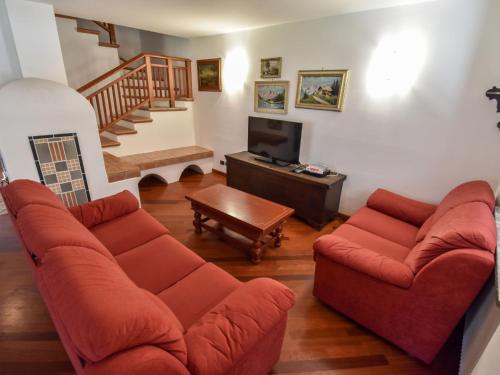 a living room with two red couches and a tv at Chalet Cesa Galadriel-1 by Interhome in Penia