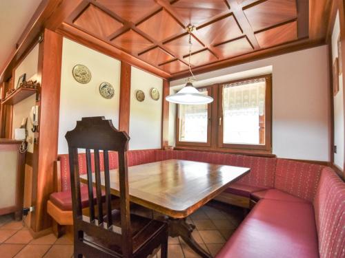 a dining room with a wooden table and a red couch at Chalet Cesa Galadriel-1 by Interhome in Penia