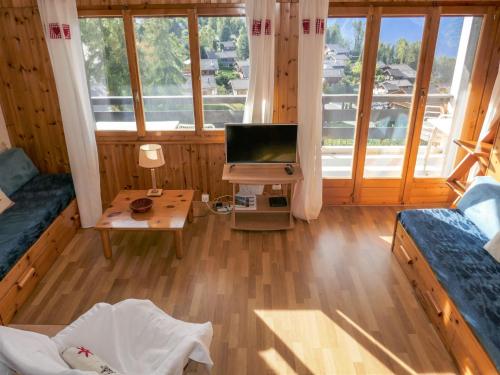 a living room with a television and a desk with a table at Apartment Chaedoz 43 by Interhome in Nendaz