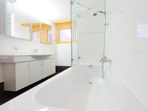 a white bathroom with a shower and a sink at Apartment Breithorn by Interhome in Zermatt