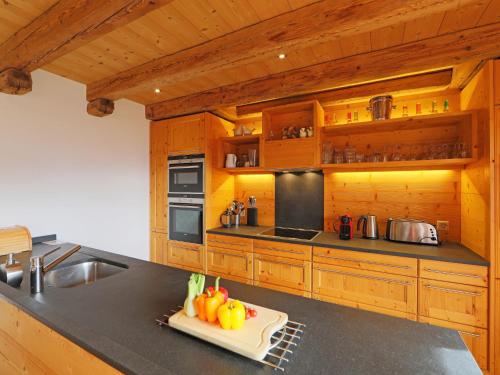 a kitchen with wooden cabinets and a cutting board with vegetables at Chalet Saint Piran-1 by Interhome in Villars-sur-Ollon