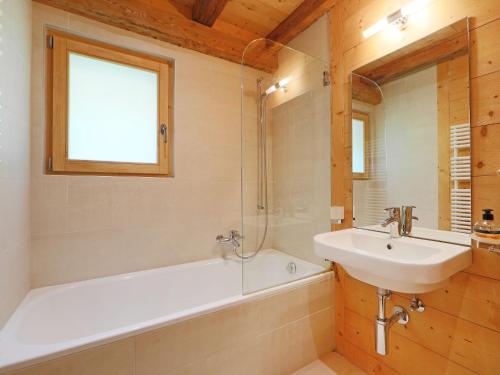 a bathroom with a sink and a bath tub and a mirror at Chalet Saint Piran-1 by Interhome in Villars-sur-Ollon