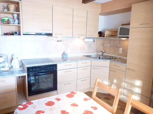 een keuken met witte kasten, een tafel en een wastafel bij Apartment Beau Site 7 by Interhome in Ovronnaz