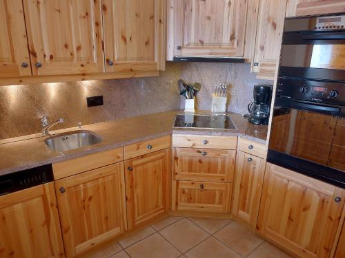 eine Küche mit Holzschränken und einem Waschbecken in der Unterkunft Apartment Rhodonite 33 by Interhome in Villars-sur-Ollon