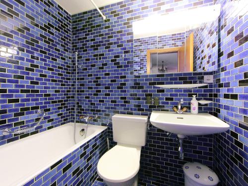 a blue tiled bathroom with a toilet and a sink at Apartment Les Faverges 8 by Interhome in Crans-Montana