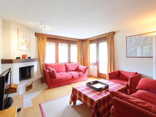 een woonkamer met een rode bank en een open haard bij Apartment Pyrith by Interhome in Zermatt