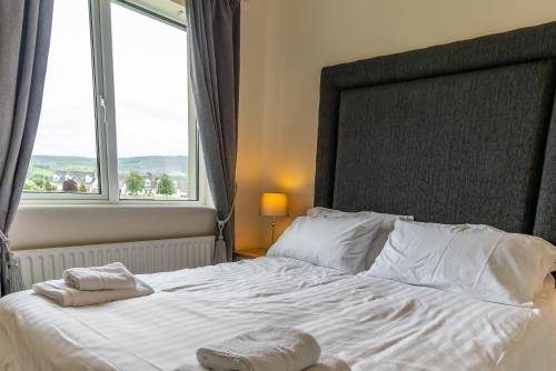 a bedroom with a large white bed with a large window at The Hawthorns, Buncrana by Wild Atlantic Wanderer in Buncrana