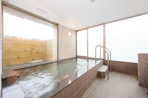 una gran piscina de agua en una habitación con ventanas en Sanco Inn Nagoya Nishiki Shikinoyu, en Nagoya