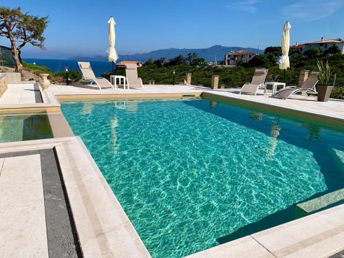 a large swimming pool with chairs and the ocean at Casa Oleandri in Tresnuraghes