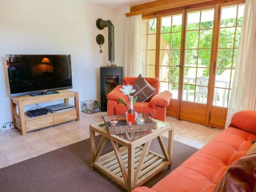sala de estar con muebles de color naranja y TV de pantalla plana. en Apartment Les Seracs 1 by Interhome, en Villars-sur-Ollon