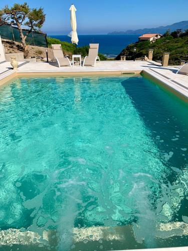 a large pool of water with chairs and an umbrella at Casa Oleandri in Tresnuraghes