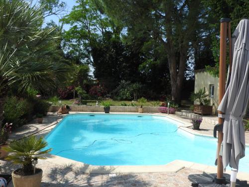 a large blue swimming pool with an umbrella at Appartement mansardé et climatisé 50 m2 in Pompignan