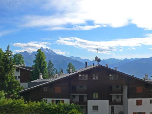 un bâtiment avec une croix sur le toit et des montagnes en arrière-plan dans l'établissement Apartment Villars Soleil A27 by Interhome, à Villars-sur-Ollon