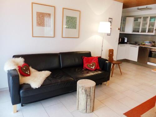 un sofá de cuero negro en una sala de estar con almohadas rojas en Apartment Chalet Almis-Bödeli-1 by Interhome, en Grindelwald