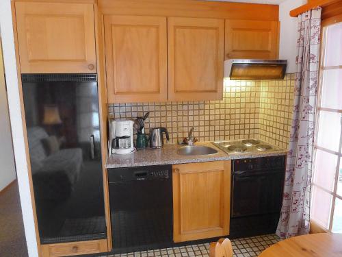 a kitchen with a black refrigerator and a sink at Apartment Le Brévent 4 by Interhome in Villars-sur-Ollon