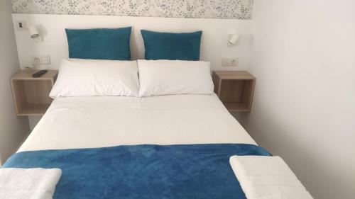 1 cama con sábanas azules y blancas y almohadas azules en PortoSantiago, en Portomarín