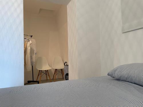a bedroom with a bed and two white chairs at Apartmani Pulić in Senj