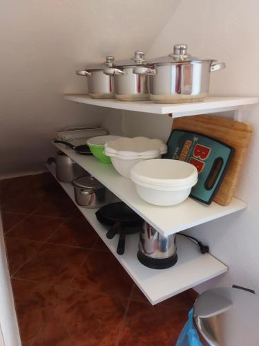 a kitchen with white shelves with pots and pans at Apartmani Jašarević in Martinšćica