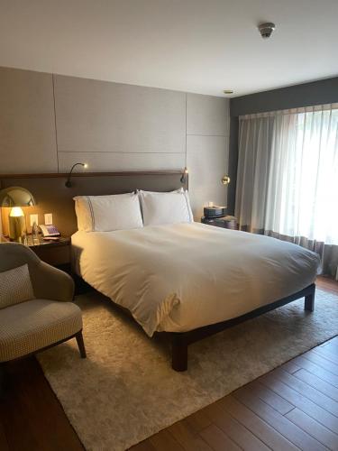 a bedroom with a large bed and a chair at Sofitel Bogota Victoria Regia in Bogotá