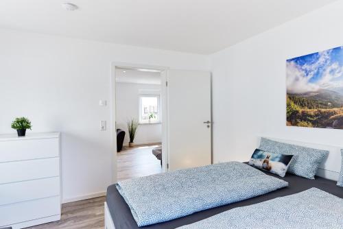 a white bedroom with a bed and a dresser at Wohnung 15 - traumhaft übernachten in Ringsheim