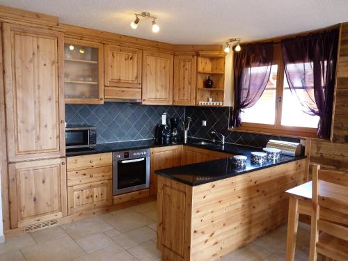 una cucina con armadi in legno e piano di lavoro nero di Apartment Ardève No 11 by Interhome a Ovronnaz