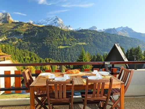a wooden table and chairs on a balcony with mountains at Apartment Anémone 2-16 by Interhome in Arveyes