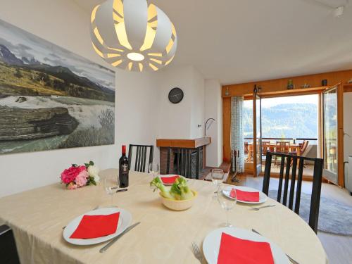 ein Esszimmer mit einem Tisch mit roten und weißen Platten in der Unterkunft Apartment Anémone 2-16 by Interhome in Arveyes