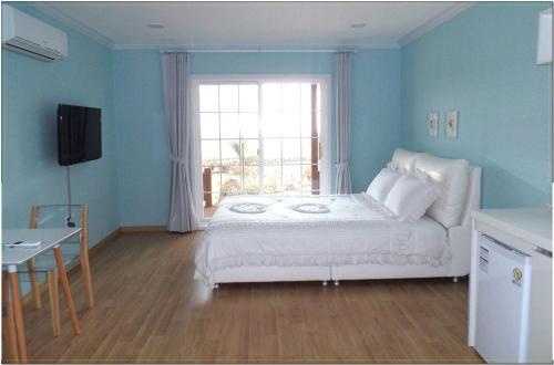 a bedroom with a white bed and a window at Jubilee Chalet in Seogwipo