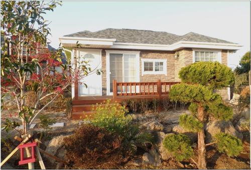 a small house with a deck in a garden at Jubilee Chalet in Seogwipo