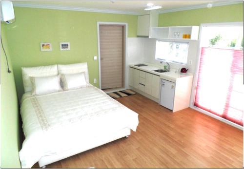 a small bedroom with a bed and a kitchen at Jubilee Chalet in Seogwipo