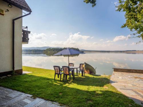 - une table avec des chaises et un parasol à côté d'un lac dans l'établissement Chalet Panorama - DEH100 by Interhome, à Dehtáře