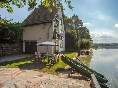 a house with a table and a canoe on the water at Chalet Panorama by Interhome in Dehtáře
