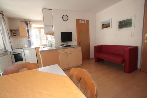 a kitchen with a red couch and a red chair at Stanzl Haus in Kaltenbach