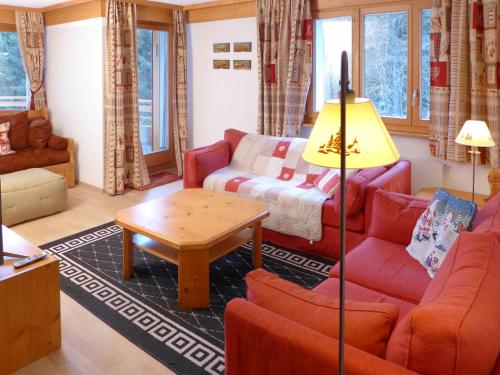 ein Wohnzimmer mit einem roten Sofa und einem Tisch in der Unterkunft Apartment Terrasse des Alpes-32 by Interhome in Crans-Montana