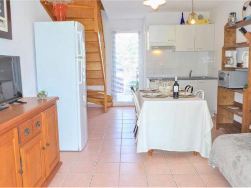 Una cocina con una mesa y un refrigerador blanco. en Holiday Home Les Jardins de la Clape-1 by Interhome, en Narbonne-Plage