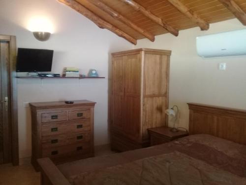 ein Schlafzimmer mit einem Bett, einem Schrank und einem TV in der Unterkunft Agua Azul poolside rest a luxurious rural woodland idyll in Cabeçadas
