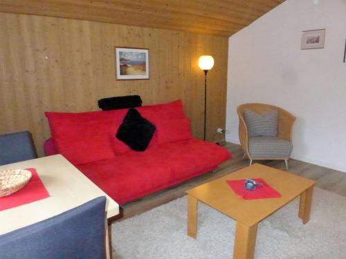 グリンデルワルトにあるApartment Chalet Doris-1 by Interhomeのリビングルーム(赤いソファ、テーブル付)