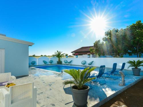 una piscina con sedie e il sole nel cielo di Apartment Jadran - NIN121 by Interhome a Nin