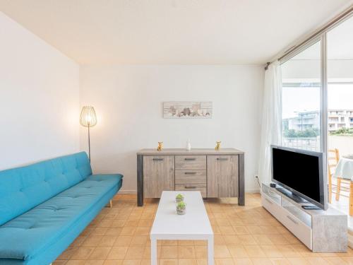a living room with a blue couch and a tv at Apartment La Méditerranée by Interhome in Narbonne-Plage