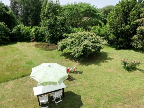 a table with an umbrella in a yard at Holiday Home Les Genêts by Interhome in Plomeur