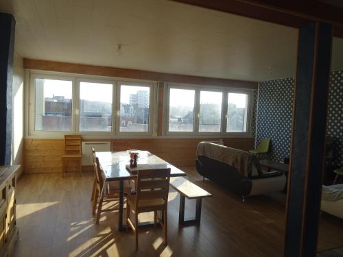 un salon avec une table, des chaises et des fenêtres dans l'établissement 85m² en hyper-centre place Dalton (3 chambres), à Boulogne-sur-Mer