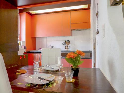 インターラーケンにあるApartment Harder by Interhomeのキッチン(オレンジ色のキャビネット、ワイングラス付きの木製テーブル付)