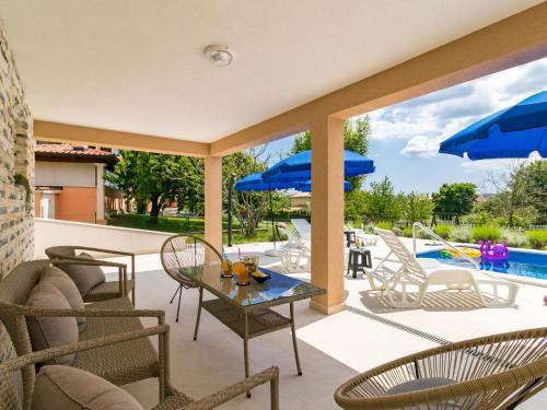 un patio avec des chaises et une table avec des parasols bleus dans l'établissement Holiday Home Marina - LBN411 by Interhome, à Labin