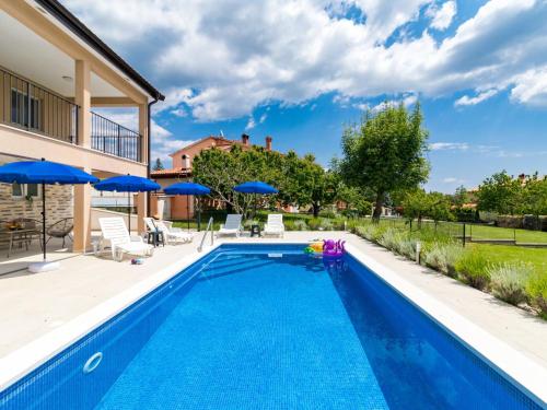- une piscine d'eau bleue dans une arrière-cour avec des parasols bleus dans l'établissement Holiday Home Marina - LBN411 by Interhome, à Labin
