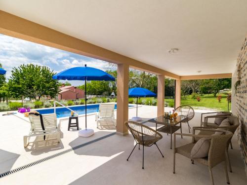 a patio with chairs and a table with blue umbrellas at Holiday Home Marina by Interhome in Labin